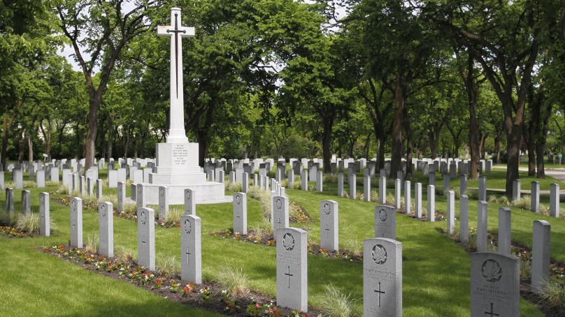 Gravestones are seen with a large white cross in the middle.