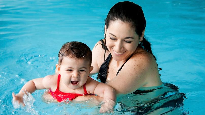 Mother teaching a baby how to swim in a pool