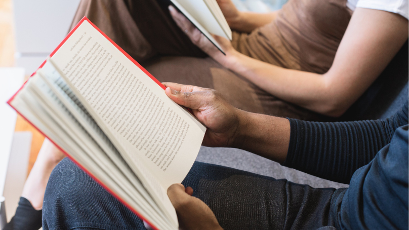 Two people sitting and reading books