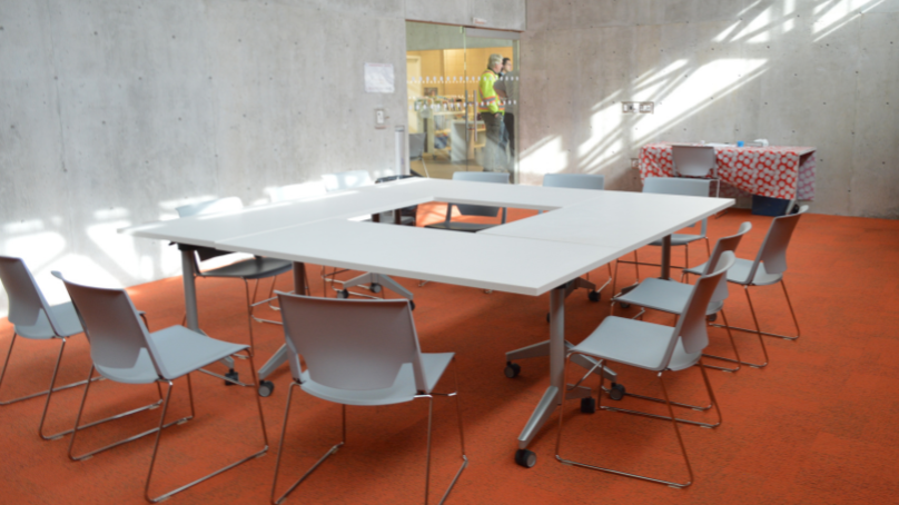 A room with a table in a circle shape with chairs around it.