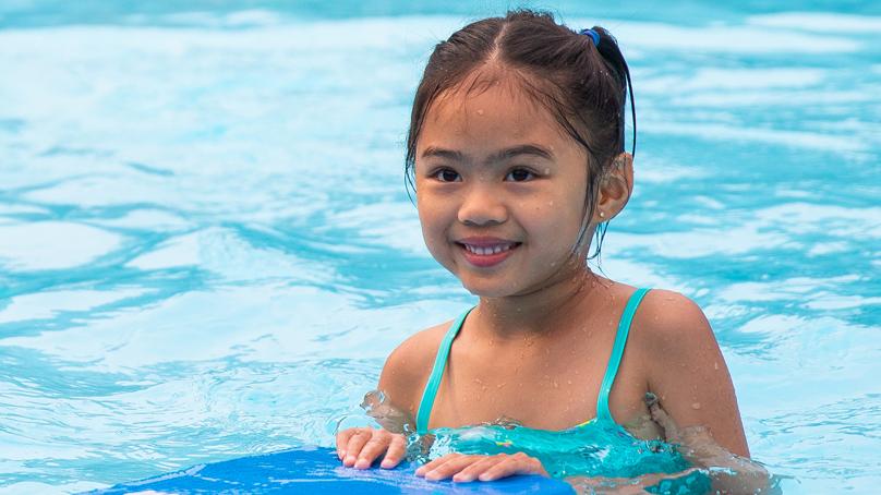 Girl in pool with flutter board at swim lessons