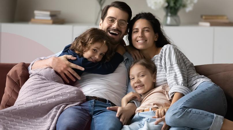 A family cuddles on the couch.