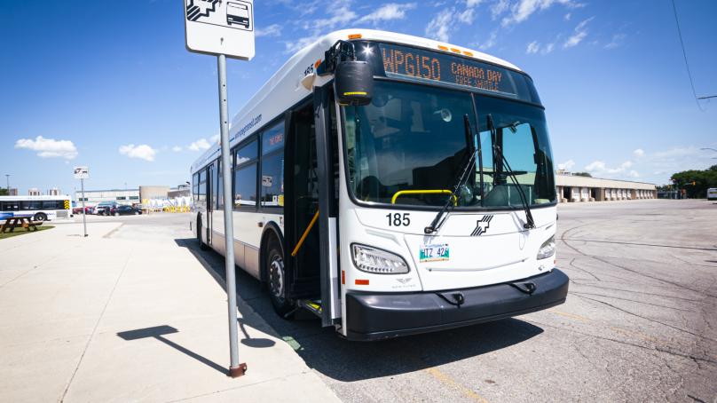 A Winnipeg Transit bus that says "Winnipeg 150" on the sign is parked at a bus stop.