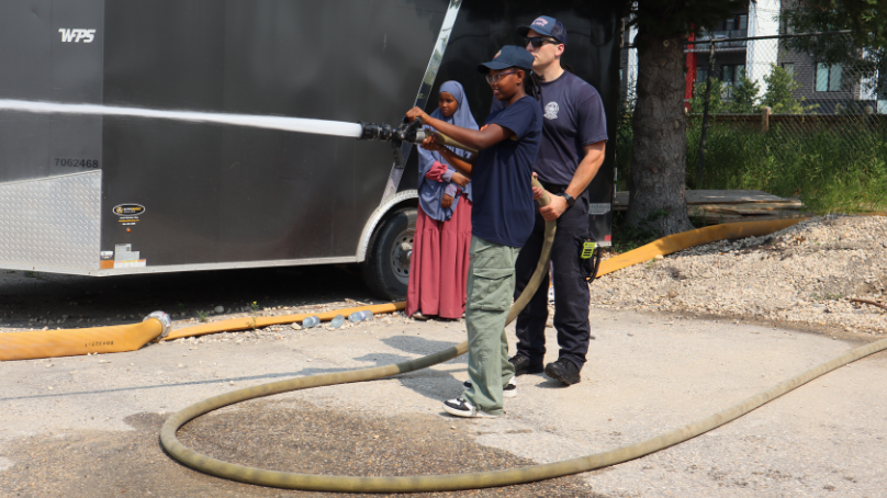 A camp participant holding a fire hose