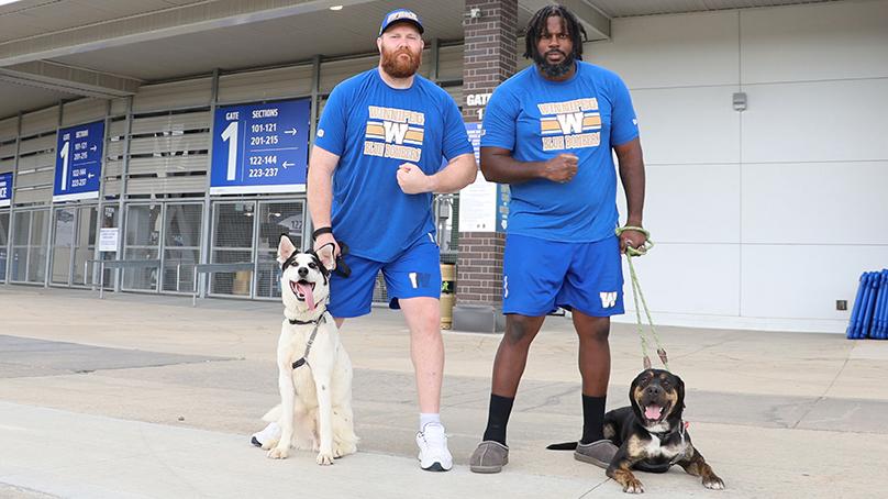 Winnipeg Blue Bomber players Pat Neufeld and Stanley Bryant pose with dogs JB and Max