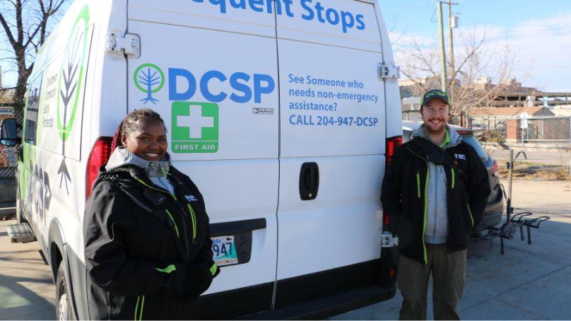 Two members of Downtown Community Safety Partnership stand in front of a white van.