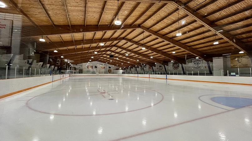 The hockey rink inside Terry Sawchuk Arena under LED lighting.
