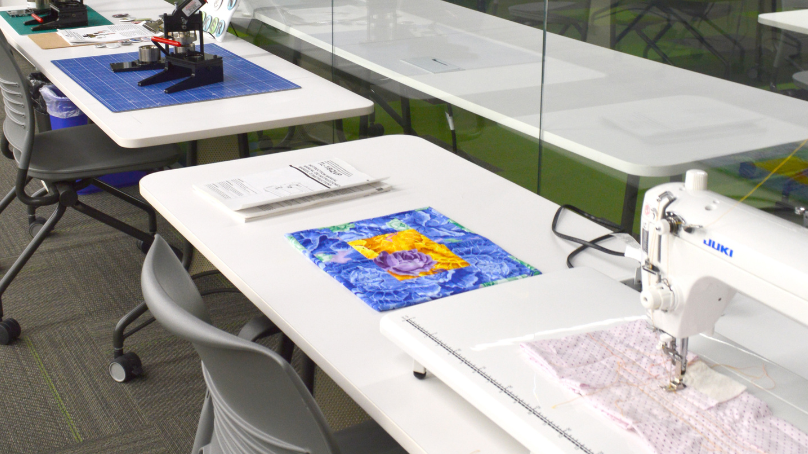 Sewing machines set up on a white table and a chair at the ideaMILL in Millennium Library.