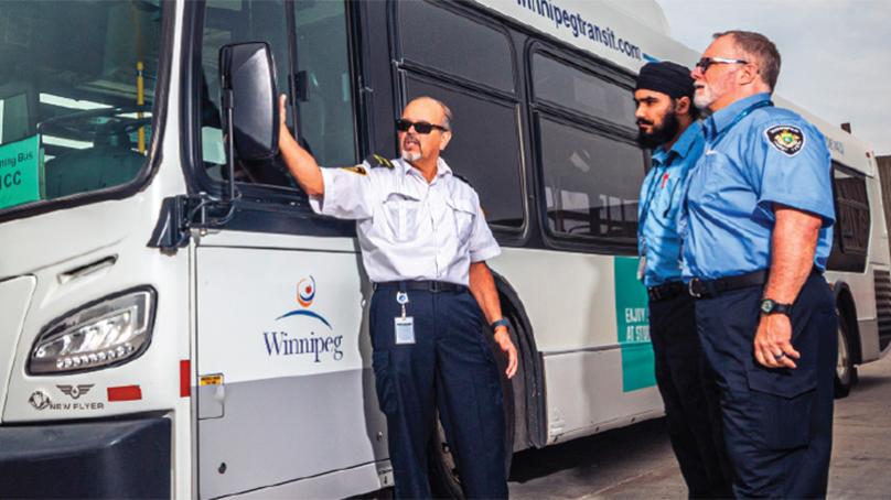 Transit employees standing beside a bus.