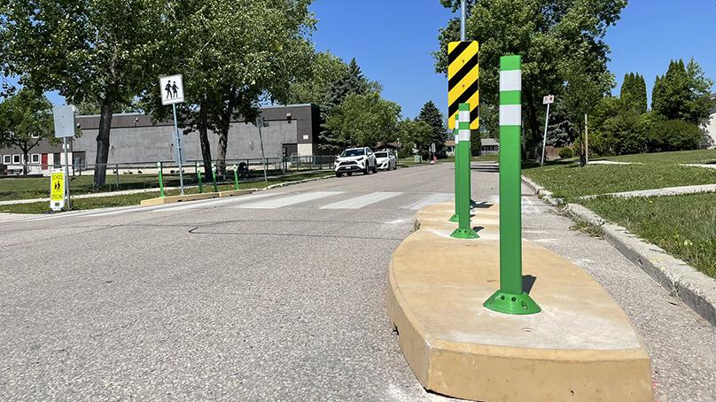 A concrete traffic calming curbs with green posts