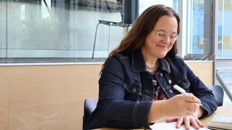 Ariel Gordon, Writer-in-Residence at Winnipeg Public Library, sitting and writing in the reading terrace at Millennium Library