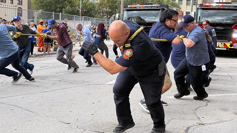 Group of people pull a fire engine with a rope.