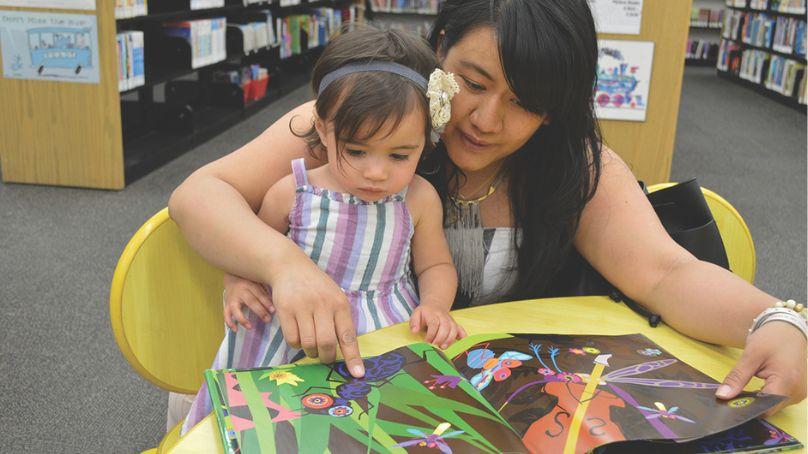 A mother and child sit and read in the children's section of Millennium Library