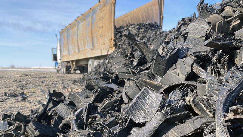 Dump truck dumping a pile of shredded tires.