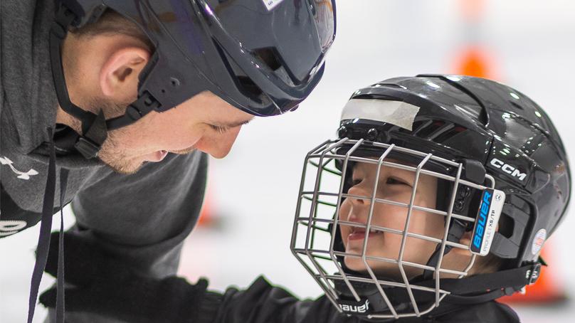 Smiling dad crouches down to speak to son at skating
