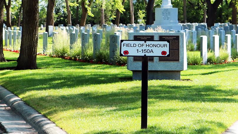 Field of Honour sign with military gravestones behind it.