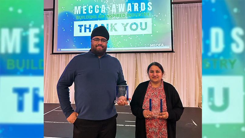 Two people standing holding awards