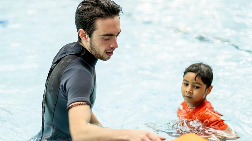 Instructor and student at swim lesson in the water at the edge of the pool