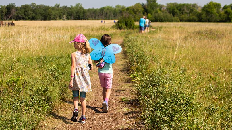 children running though a field wearing paper butterfly wings