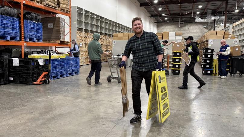 Person carrying voting location signs in a warehouse