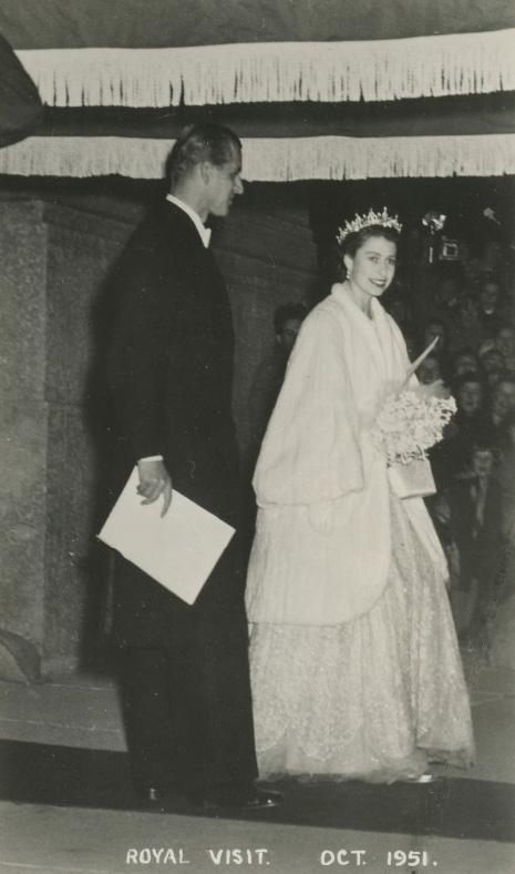Princess Elizabeth, Duchess of Edinburgh (later Queen Elizabeth II) and the Duke of Edinburgh (or Prince Philip) walk on a red carpet.