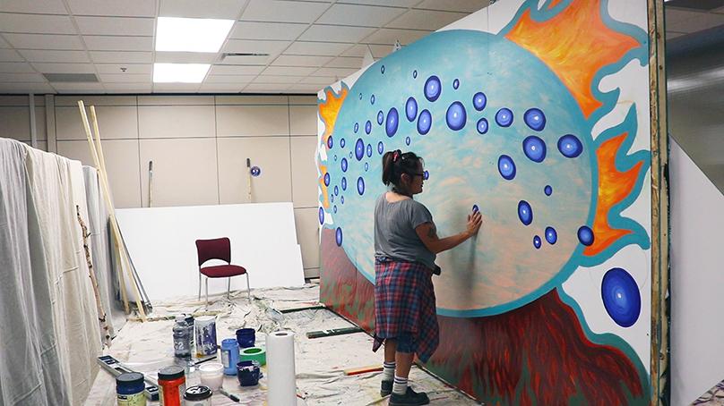 Jeannie White Bird works on the mural.