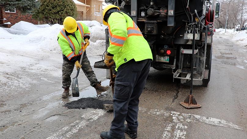 Crews repair a pothole with a temporary patches using cold mix, an asphalt mix specifically designed for use in cold, wet weather.