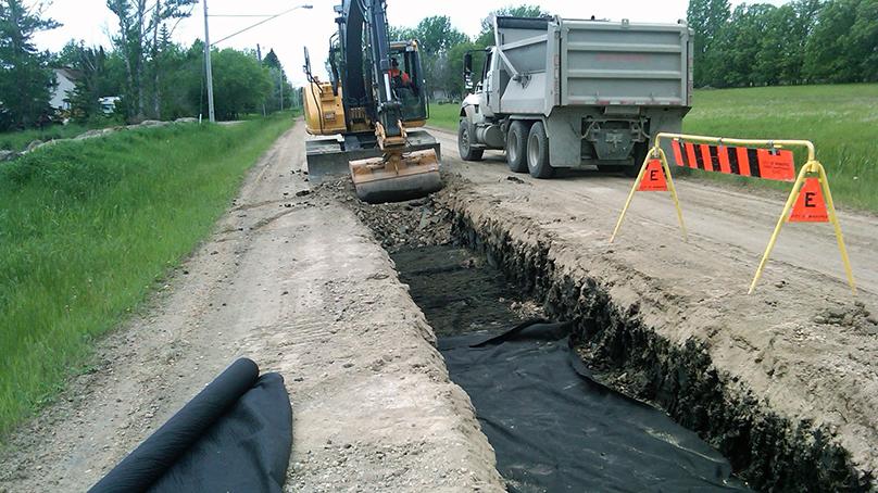 Crews work on a section of a gravel road.