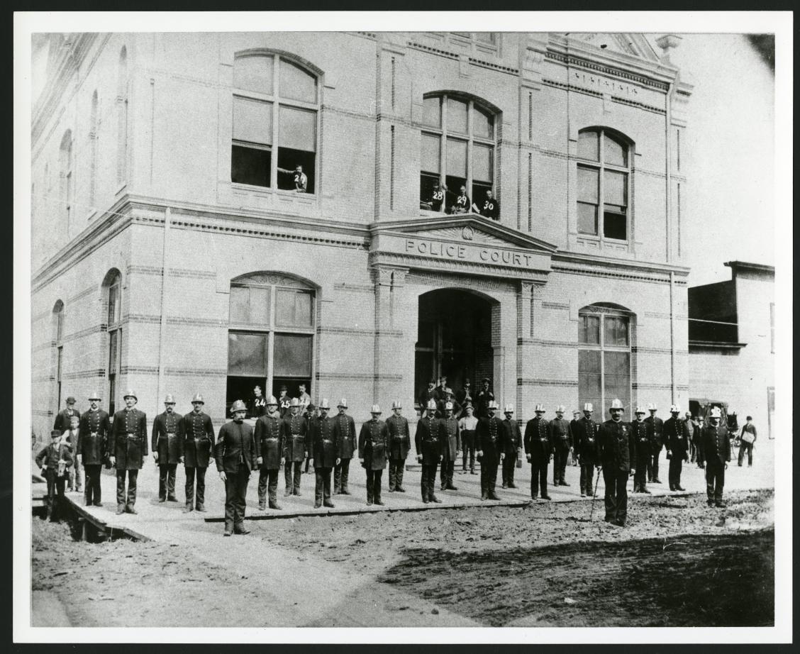 A photograph of policemen standing in front of the Police Station on James Avenue, taken in 1885.