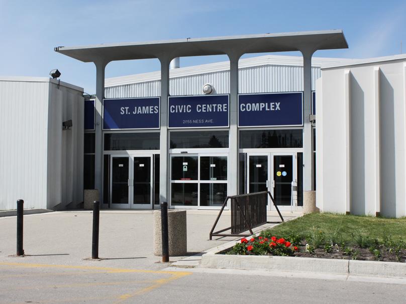 Red flowers decorate the lawn near the front entrance of the St. James Civic Centre on a sunny summer day. 