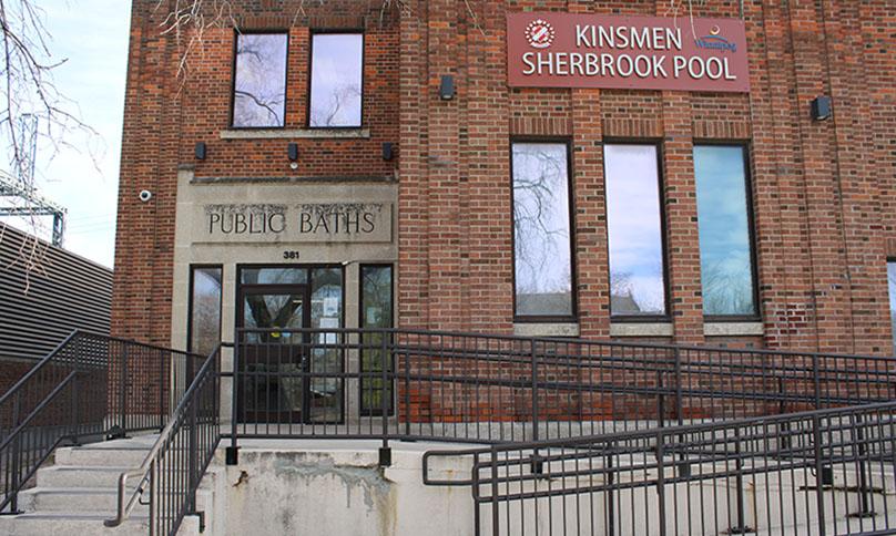 A wheelchair ramp and stairs lead to the doors of the Kinsmen Sherbrook Pool.