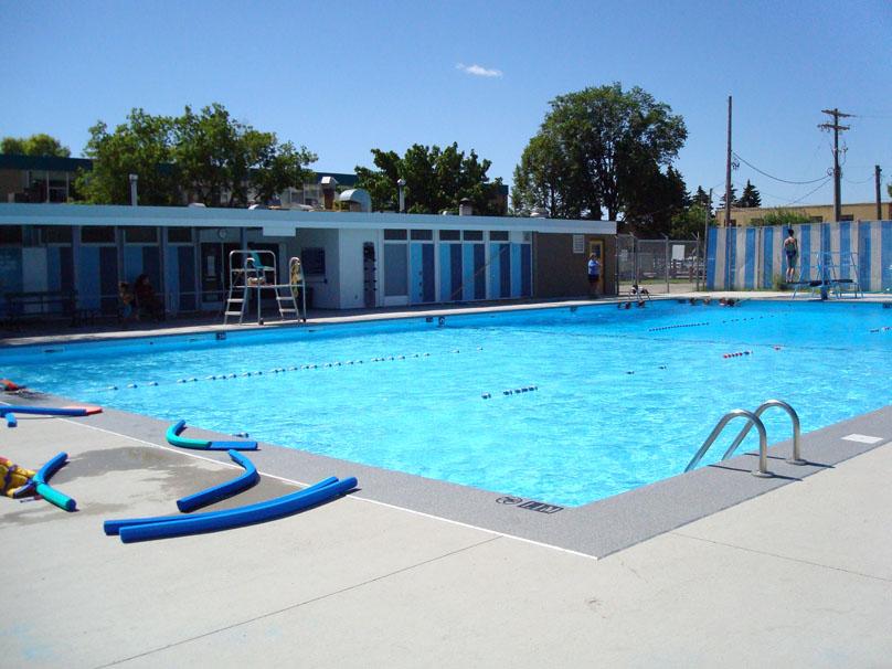 Fort Garry Lions Pool on a sunny day, with pool noodles arranged on the pool deck.
