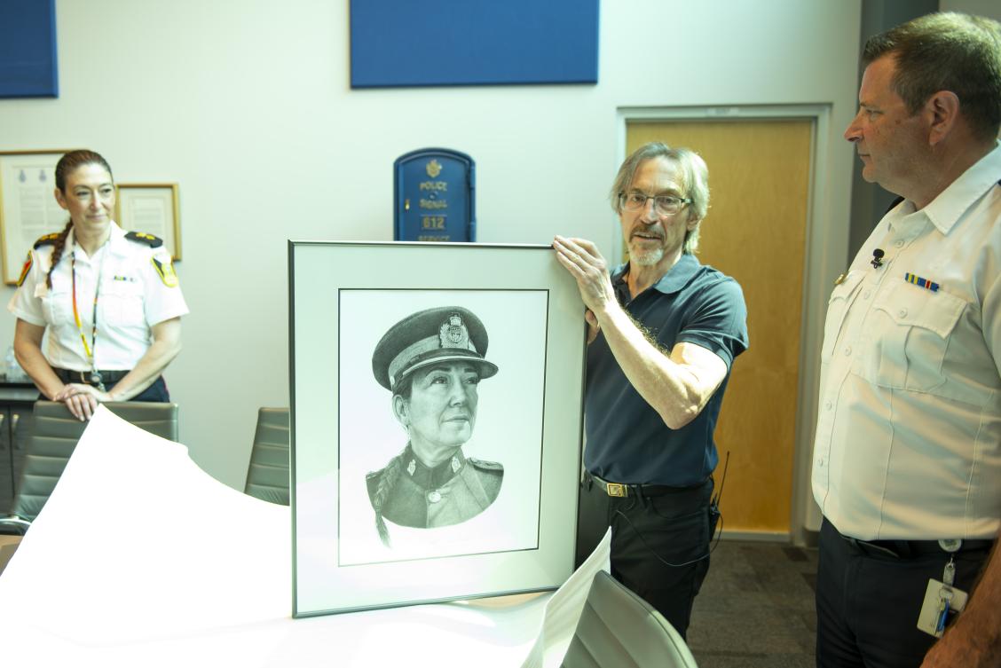 Superintendent Emerson and Chief Gene Bowers are on hand as artist Gerald Kuehl unveils his sketch of Sup. Emerson.