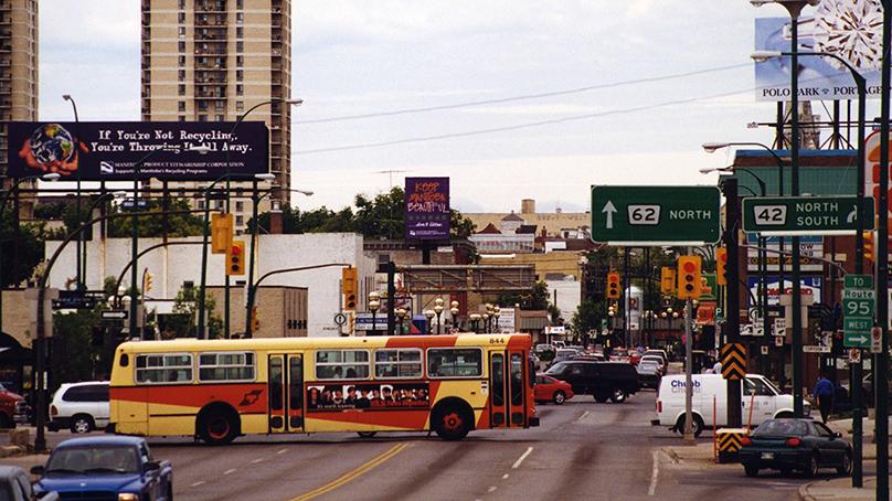 Bus No. 844 heads east through the Confusion Corner intersection. Osborne Village is in the background. Taken in 2000.